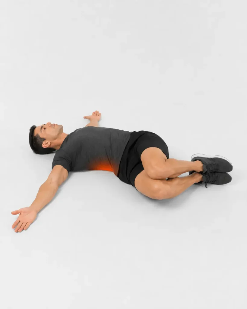 Hombre tumbado realizando una rotación lumbar suave con las rodillas hacia un lado